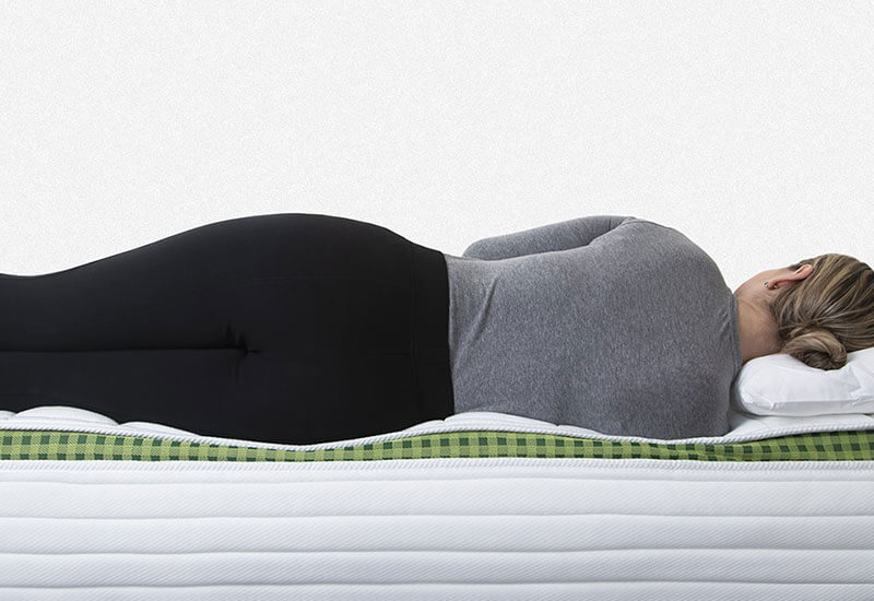 Image of a woman lying on the side edge of the Brunswick spring mattress showing the zones of support.