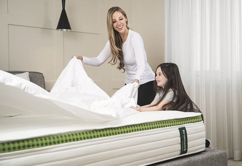Image of a mother and daughter having fun changing the sheets on their Brunswick spring mattress.