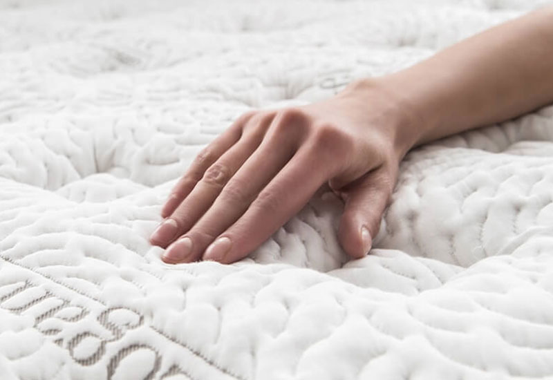 Image of a hand brushing the smooth quilted surface of the Logan & Cove luxury hybrid pillow-top mattress.