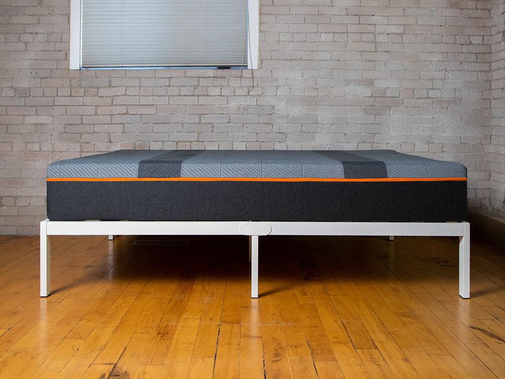 Image of the side of the Recore performance latex mattress on a white bed frame in a loft apartment.