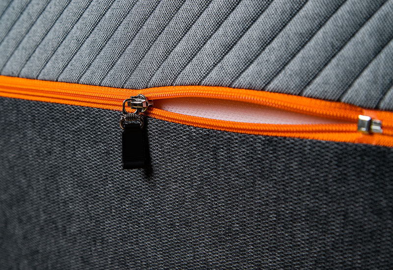 Close-up image of the orange cover zipper slightly undone on the Recore latex mattress.