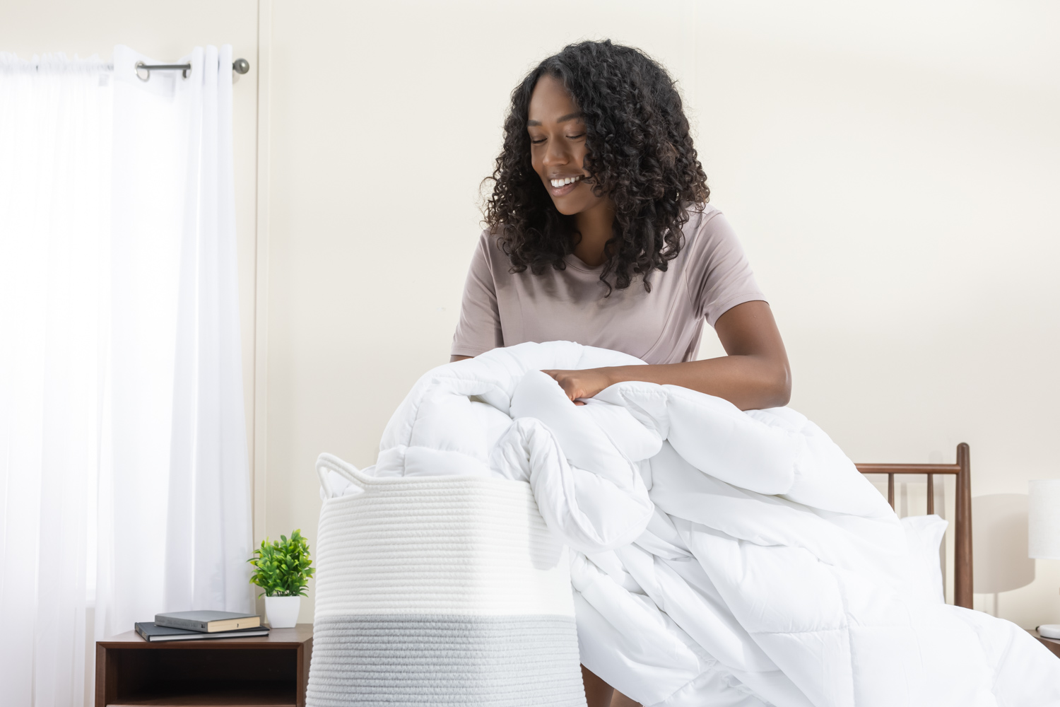 Une femme met sa couette en duvet synthétique dans le panier de lavage 