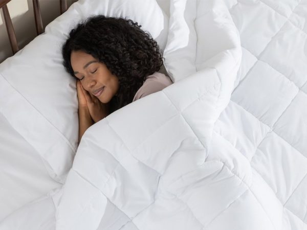 Une femme dort paisiblement sous sa couette en duvet synthétique